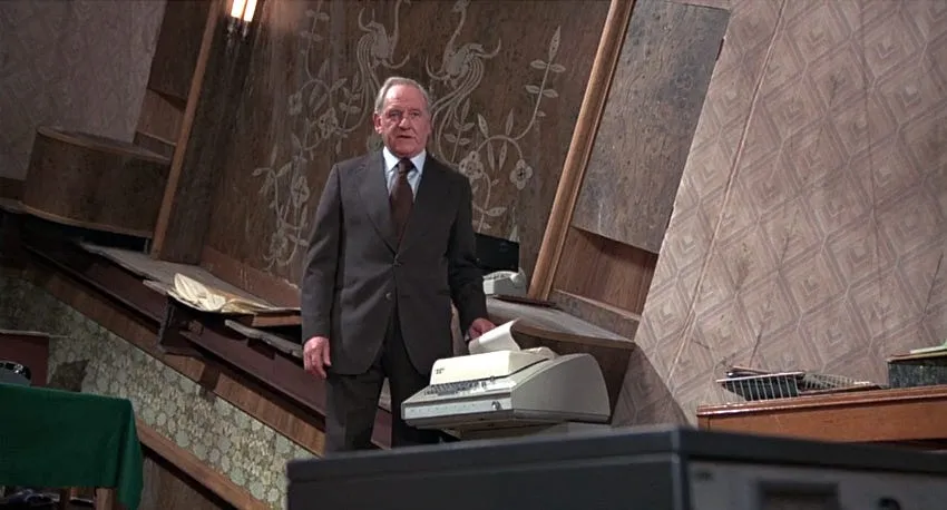 M stands in the hilariously askew interior of MI6's half-sunken ship headquarters in The Man with the Golden Gun