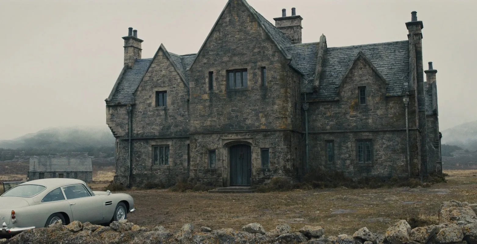 The Aston Martin DB5 parked outside the grey stone Skyfall lodge on the bleak Scottish moors